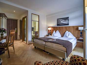 Neat hotel room with double bed, desk, chair, and wooden furnishings in neutral tones, content_suitable":true}