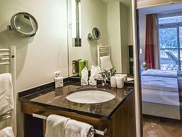 Modern bathroom vanity with sink, mirrors, towels, and a view into a bedroom balcony area, true}