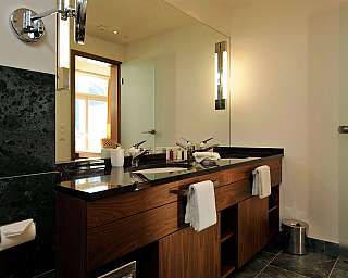 Modernes Badezimmer mit Holzwaschtisch, zwei Waschbecken, großem Spiegel und Handtüchern an den Griffen