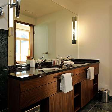 Modernes Badezimmer mit Holzwaschtisch, zwei Waschbecken, großem Spiegel und Handtüchern an den Griffen