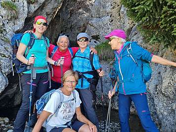 Fünf Frauen mit Wanderstöcken stehen vor Felswänden auf einem Bergpfad.