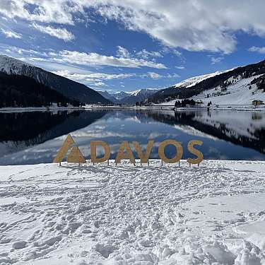 Schneebedecktes Tal mit See, Bergen und Holzschriftzug am Ufer