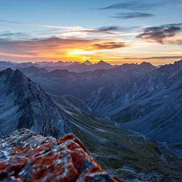 Blick über zerklüftete Berge und ein Tal bei Sonnenaufgang.