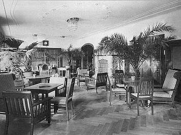 Spacious lounge with wooden chairs, small tables