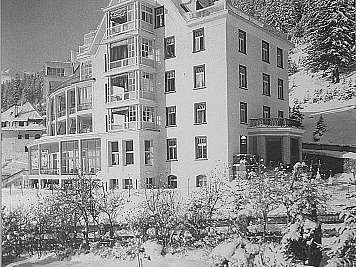 Large white hotel with balconies on a snowy hillside