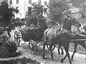 Horse-drawn carriage with driver and passenger traveling