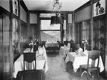 A black-and-white dining room with set tables, chairs, floral arrangements