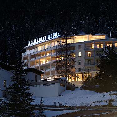 Large hotel building glowing in snowy forest at night