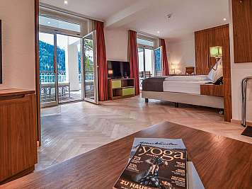 Spacious hotel room with bed, balcony doors, and mountain view