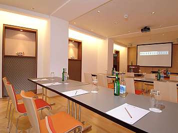 Conference room with tables, chairs, notepads, bottles, and a projection screen