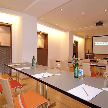 Conference room with tables, chairs, notepads, bottles, and a projection screen