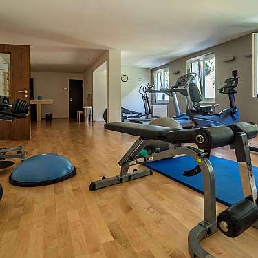 Heller Trainingsraum mit verschiedenen Fitnessgeräten, Matten und großen Fenstern.