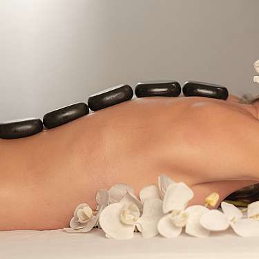 Person receiving a hot stone massage with flowers nearby