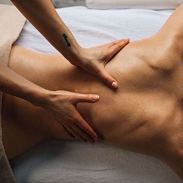 Person erhält eine Massage am Rücken auf einer Behandlungsliege.