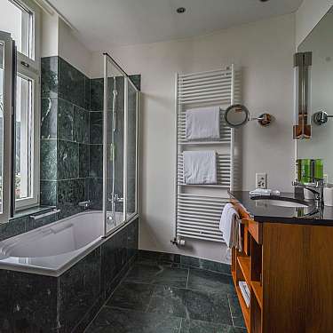 Modernes Badezimmer mit Fenster, Badewanne, Dusche, Waschbecken und Handtuchheizkörper.