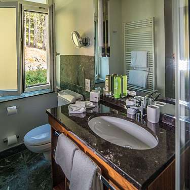 Fliesenbad mit Waschbecken, Spiegel, Toilette und Blick auf verschneite Bäume