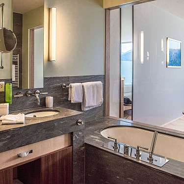 Modern hotel bathroom with double sink, bathtub, and large mirror.