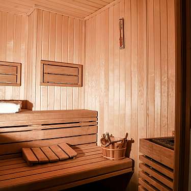 Empty wooden sauna with bench, towel, bucket, and thermometer