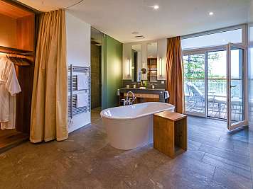 Modernes Badezimmer mit freistehender Badewanne, Holzregalen, Spiegel und begehbarer Dusche.