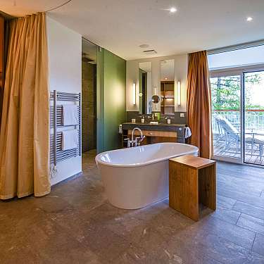 Spacious bathroom with freestanding bathtub, wooden shelving, mirror, and walk-in shower.