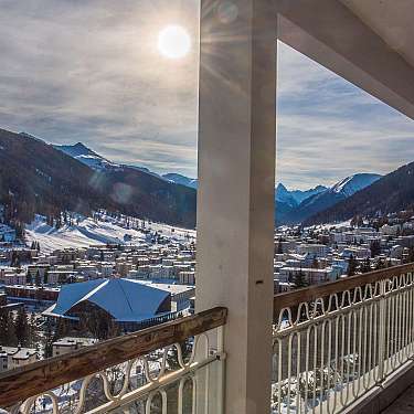 View from a balcony over a snowy mountain town and surrounding peaks