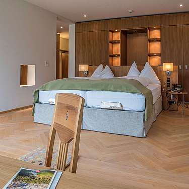 Modern eingerichtetes Schlafzimmer mit großem Bett, Holzverkleidung und warmen Lampen.