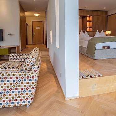 Modernes Hotelzimmer mit Sitzecke, Fernseher und großem Bett