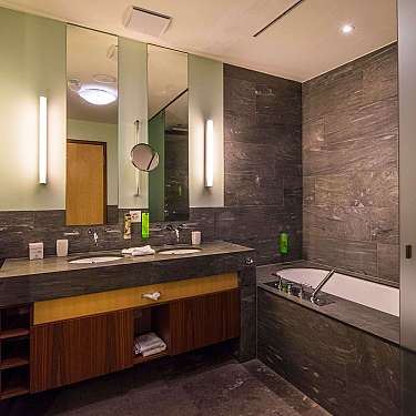 Modernes Badezimmer mit Doppelwaschbecken, großer Spiegelwand und eingelassener Badewanne.